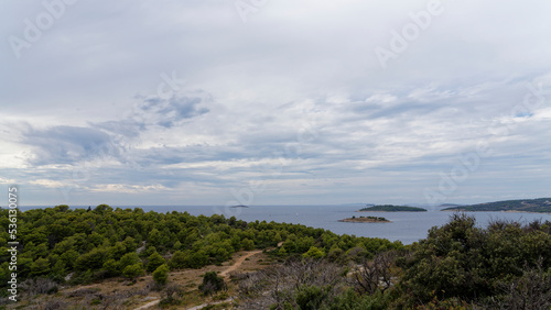 Croatian Mediterranean coast photographed from a lookout mountain near Rogoznica. In the foreground forest with hiking trails, in the background the blue sea with many small islands.