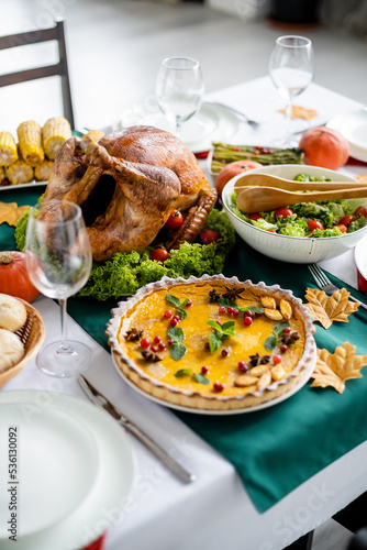delicious roasted turkey near traditional pumpkin pie with cranberries and mint leaves served for thanksgiving dinner