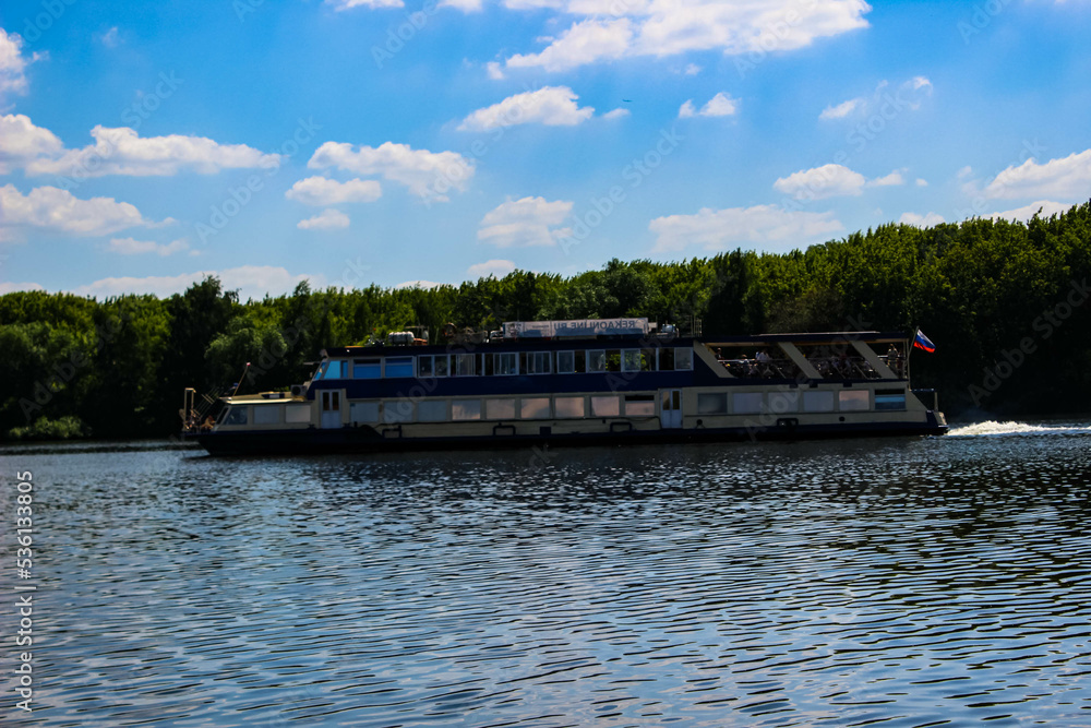 A huge tourist boat with a Russian flag floating on the river