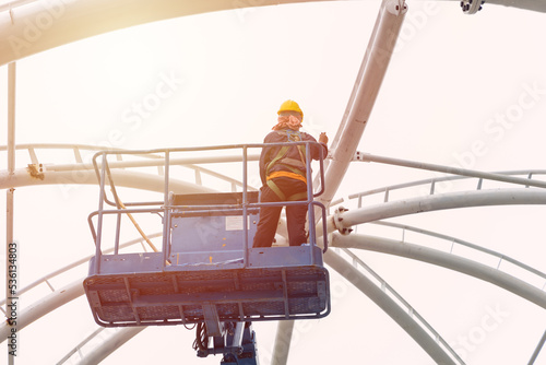Fotografi construction worker work at high construction roof on crane platform lift with s