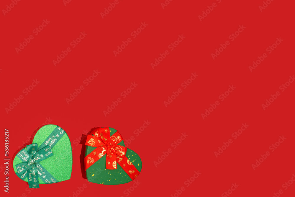 Green and red Christmas boxes on vibrant red background. Concept of love, Winter holidays, gift, beloved, surprise, present, feelings. Copy space. Green and red Christmas boxes on vibrant red background. Concept of love, Winter holidays, gift, beloved, surprise, present, feelings. Copy space.