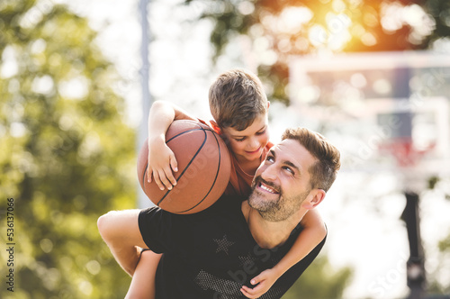 Fototapeta Naklejka Na Ścianę i Meble -  man and young boy playing basketball on a court, teaching little player and spending time outdoors