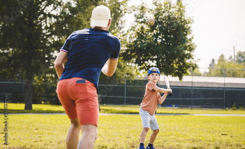 Father and son playing baseball in sunny day at public park photo