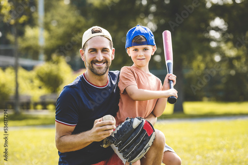 Father and son playing baseball in sunny day at public park photo