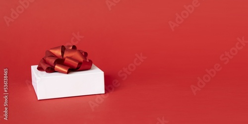 white gift box with red ribbon bow on red background. present for Christmas, new year, valentine day
