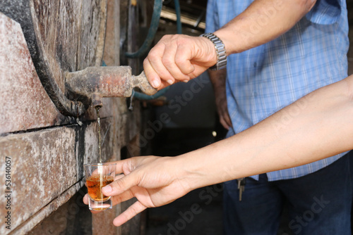 hand opening wooden barrel pouring alcohol into a small glass. Brazilian export beverage. Brazilian product for export, distilled beverage known as cognac, pinga or cachaça photo