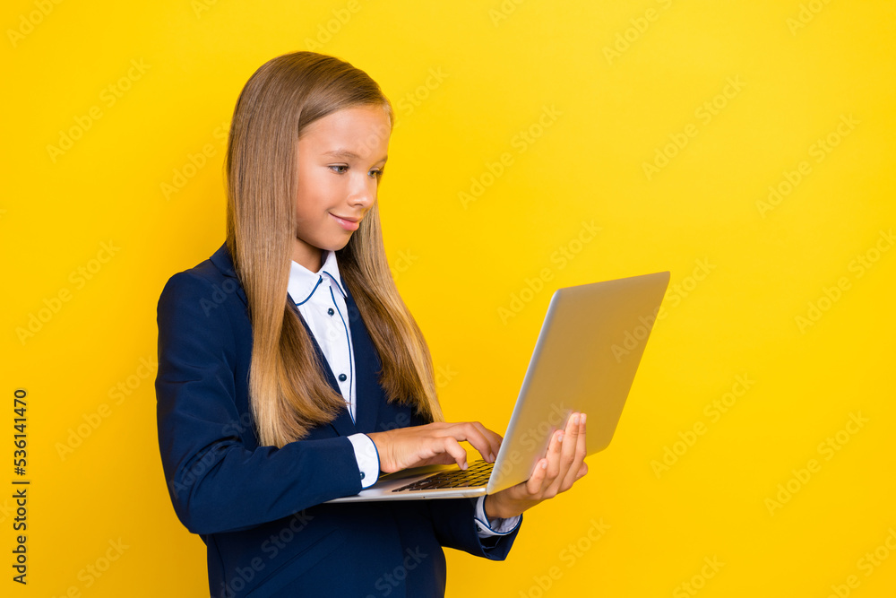 Photo of smart clever positive girl hold use netbook chatting texting classmates friends empty space isolated on yellow color background Photo of smart clever positive girl hold use netbook chatting texting classmates friends empty space isolated on yellow color background