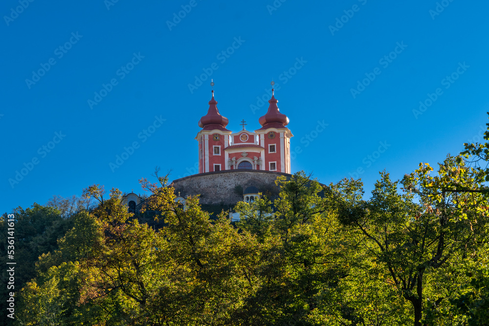 view of the red Calvary Banska Stiavnica under a blue sky with forest in foreground