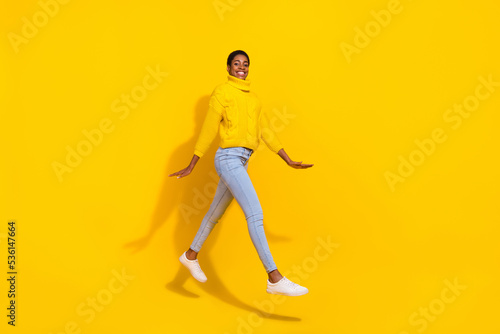 Full length body size view of attractive cheerful trendy slender skinny girl jumping going isolated over bright yellow color background