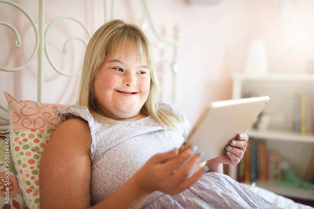Beautiful little child girl in a dress having great time on her pink bedroom with tablet Beautiful little child girl in a dress having great time on her pink bedroom with tablet