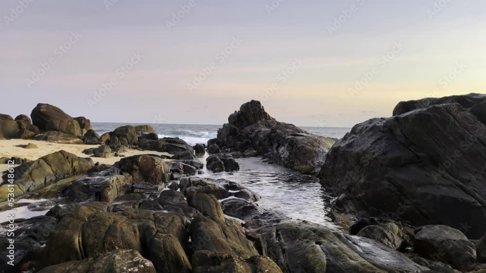the waves of the ocean beat against the rocky shore at sunset the waves of the ocean beat against the rocky shore at sunset