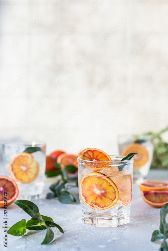 Hard seltzer cocktail with blood orange. Cocktail or lemonade with fresh citrus. Refreshing drink, low alcohol mocktails. Party concept. Shadow and sunlight. Hard seltzer cocktail with blood orange. Cocktail or lemonade with fresh citrus. Refreshing drink, low alcohol mocktails. Party concept. Shadow and sunlight.