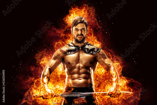 Sportive man in leather warrior costume with sword, fire on background