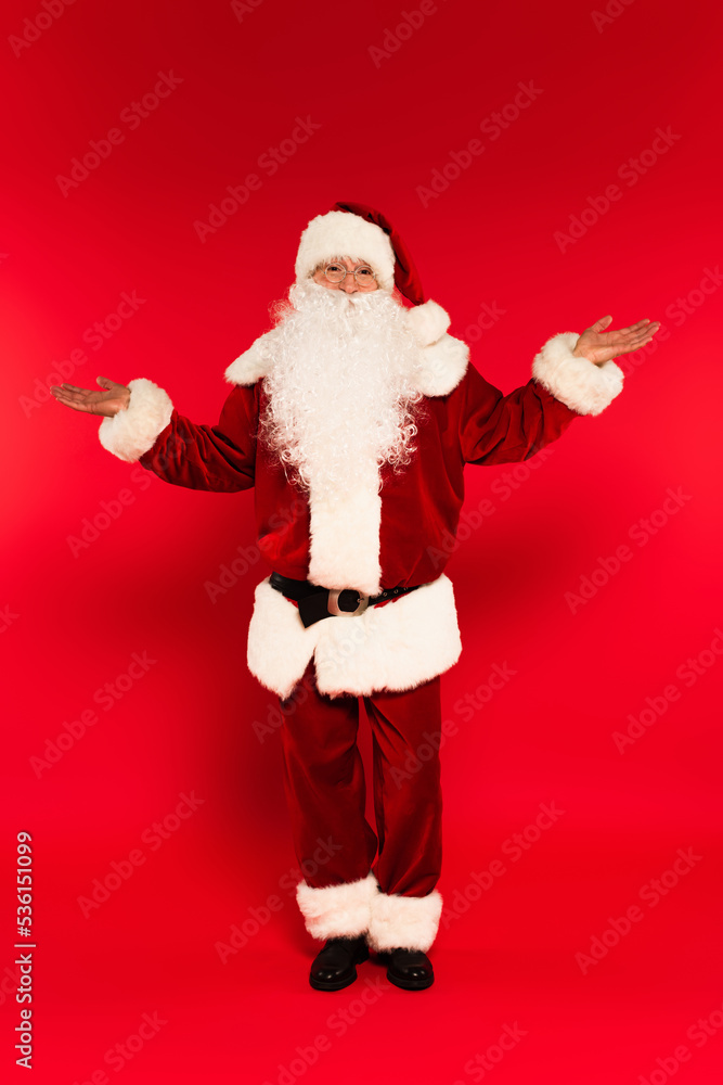Father christmas in costume pointing with hands on red background. Father christmas in costume pointing with hands on red background.