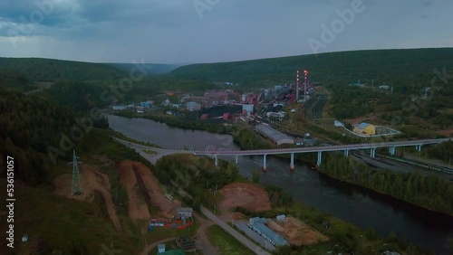Flying above the river through small town and mountain landscape. Clip. Bridge across the wide river leading to the town. photo