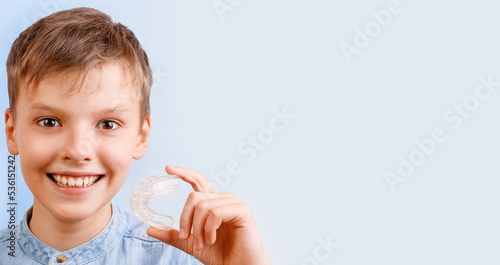 Obraz na plátne Positive child boy is holding mouth guards for his teeth and smiling