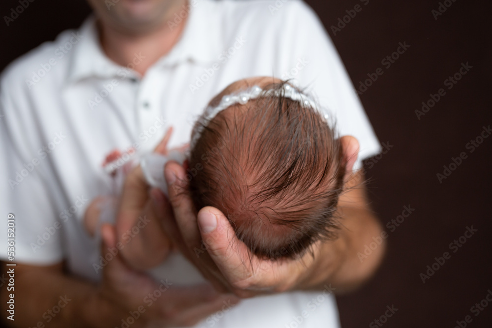 the head of a newborn in the palm of his father. small head of a newborn. child in the arms of a parent the head of a newborn in the palm of his father. small head of a newborn. child in the arms of a parent