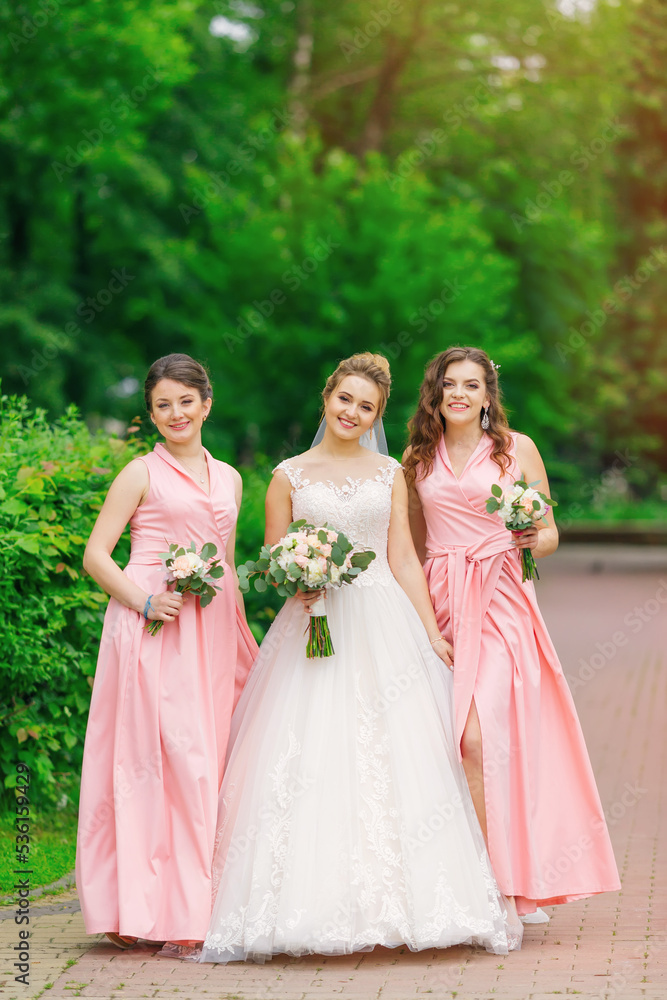 Bride with bridesmaids in the park on the wedding day. girls hol
