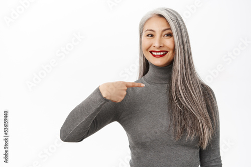 Foto Portrait of smiling happy asian lady, middle aged woman pointing at herself with