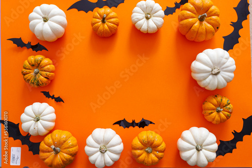 Halloween flat lay composition of black paper bats and pumpkins on orange background. Halloween concept