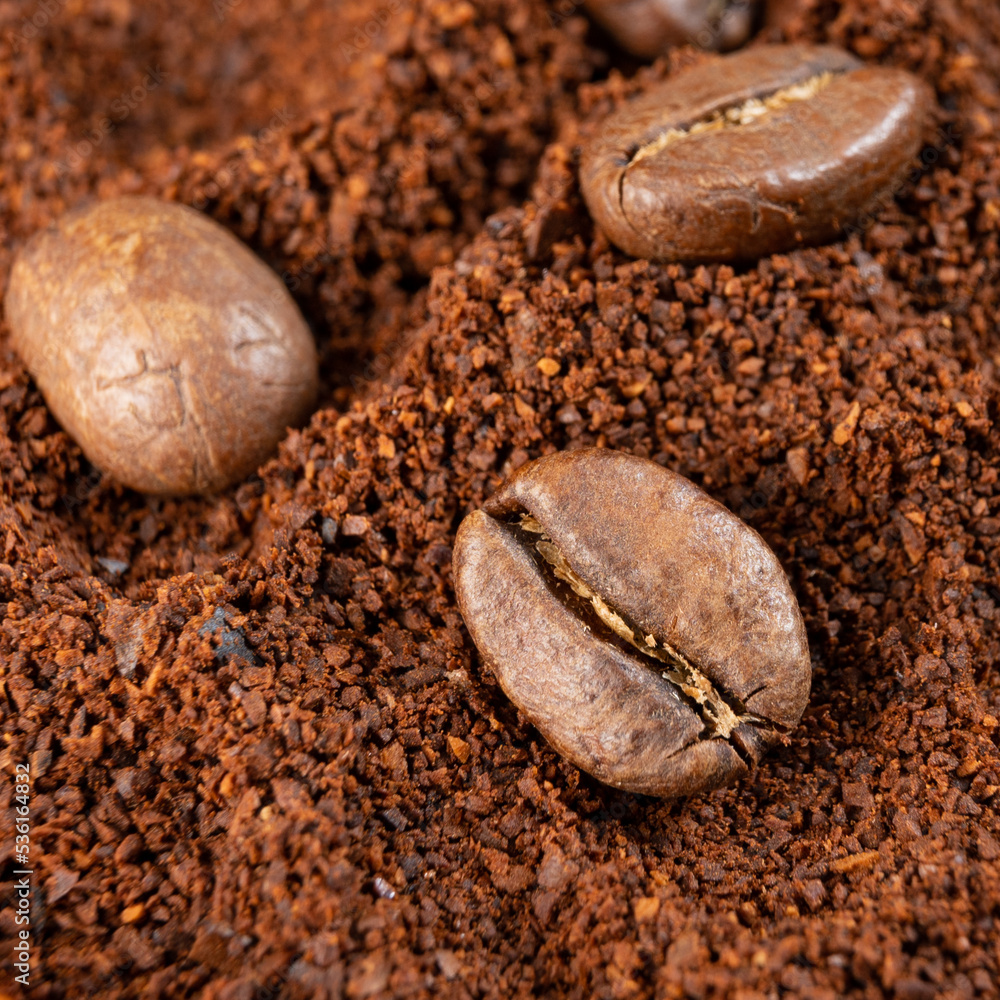 Fototapeta premium Three coffee beans lie on ground coffee close-up.