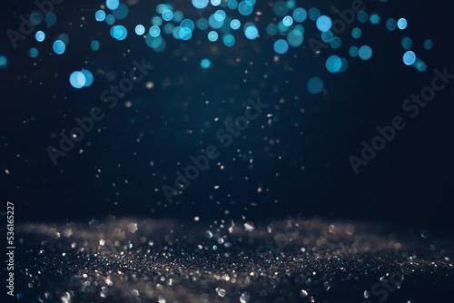 Glowing in the dark defocused glitter texture with blue bokeh lights and snow. Christmas and winter holidays background