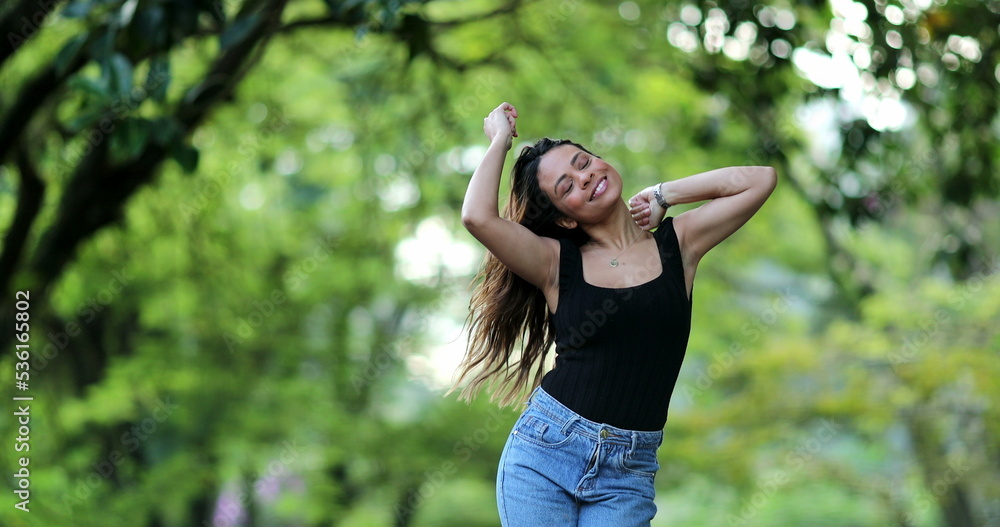 Happy woman dancing with joy outside, free mixed race girl dance, person jumping with joy