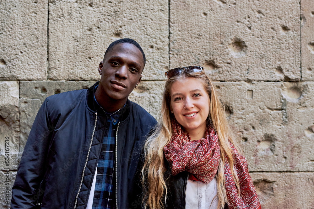 Beautiful smiling couple looking at camera over stone wall. Beautiful smiling couple looking at camera over stone wall.