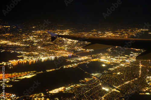 Night city in golden lights from the window of an airplane flying high in the sky. Beautiful landscape. Megapolis. Abstraction. Vacation, tourism, travel, map.