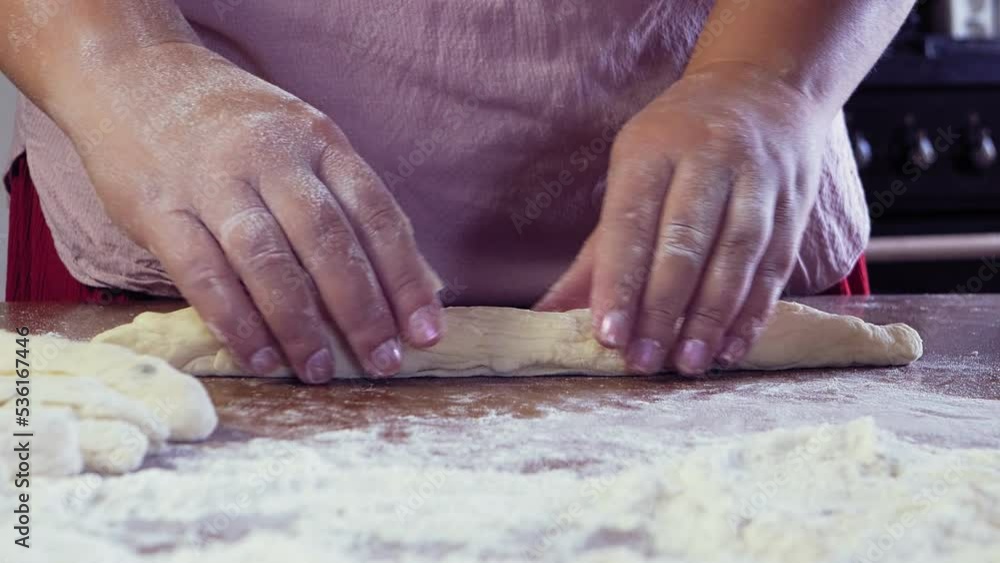The hands of a Jewish woman form blanks of dough for the festive Challah on the table. Medium plan The hands of a Jewish woman form blanks of dough for the festive Challah on the table. Medium plan