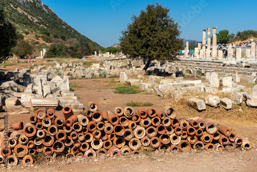 Old Roman plumbing clay pipes at Ephesus in Turkey and the ruins of the Bazilica Stoa in the background.  photo