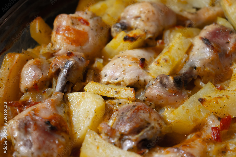 Baked hot potatoes with chicken legs only from the oven. A dish cooked at home. Hot fat and juice heats up, squirts and bubbles on a baking sheet Baked hot potatoes with chicken legs only from the oven. A dish cooked at home. Hot fat and juice heats up, squirts and bubbles on a baking sheet