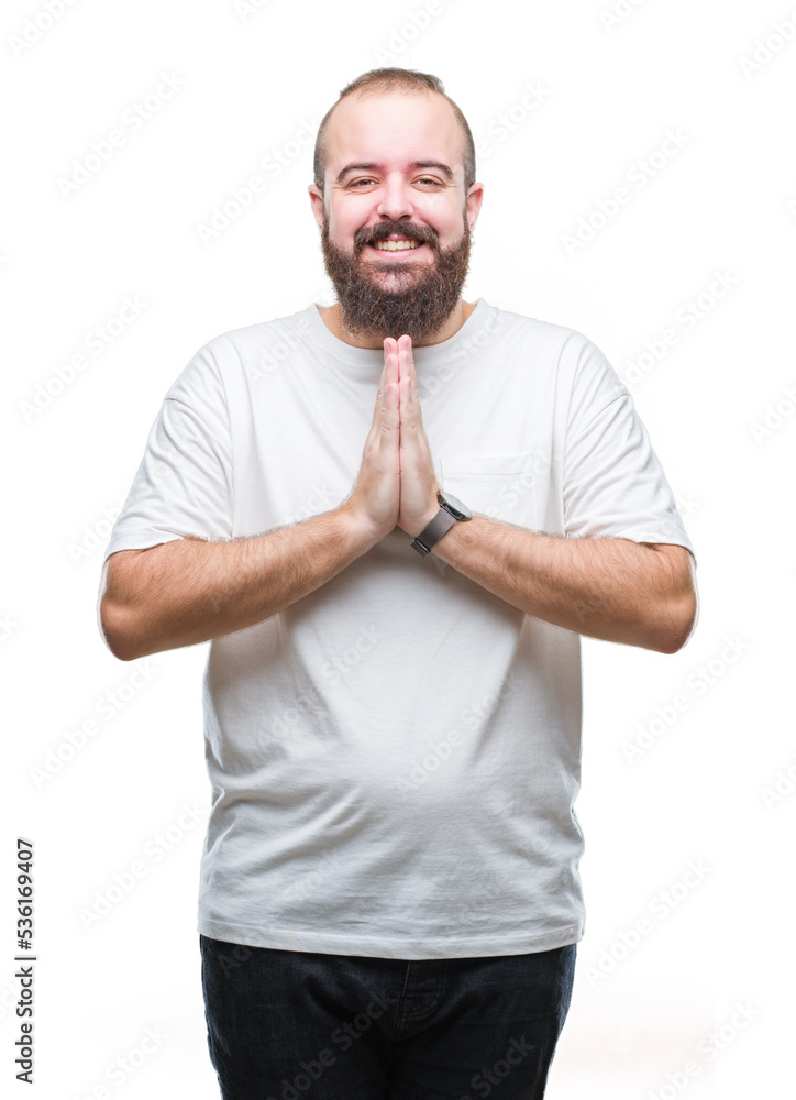 Young caucasian hipster man wearing casual t-shirt over isolated background praying with hands together asking for forgiveness smiling confident. Young caucasian hipster man wearing casual t-shirt over isolated background praying with hands together asking for forgiveness smiling confident.