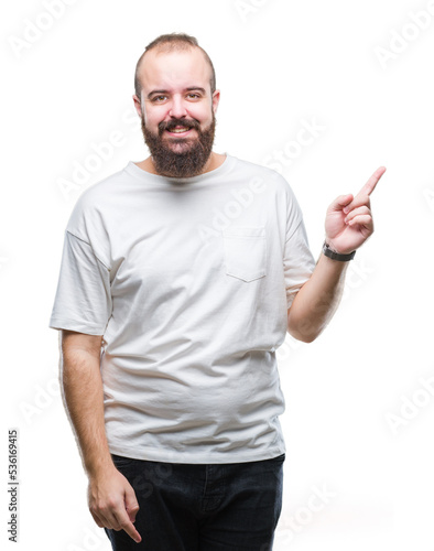 Young caucasian hipster man wearing casual t-shirt over isolated background with a big smile on face, pointing with hand and finger to the side looking at the camera.