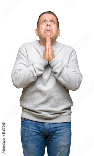 Middle age arab man wearing sport sweatshirt over isolated background begging and praying with hands together with hope expression on face very emotional and worried. Asking for forgiveness © Krakenimages.com