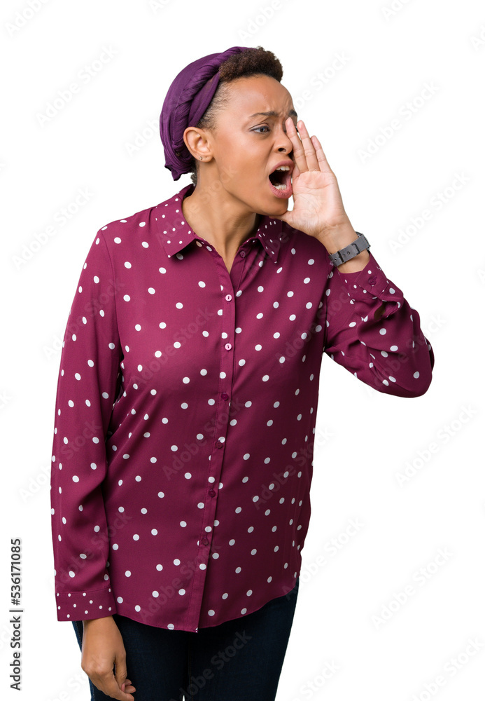 Beautiful young african american woman wearing head scarf over isolated background shouting and screaming loud to side with hand on mouth. Communication concept. Beautiful young african american woman wearing head scarf over isolated background shouting and screaming loud to side with hand on mouth. Communication concept.