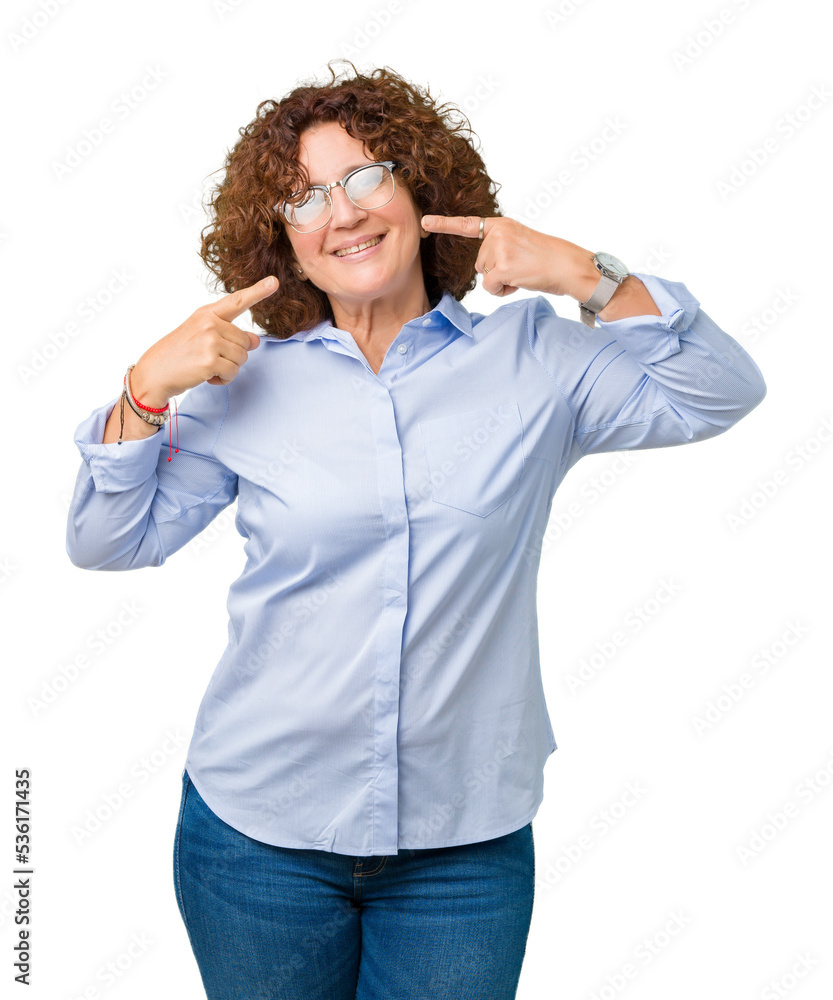 Beautiful middle ager senior businees woman wearing glasses over isolated background smiling confident showing and pointing with fingers teeth and mouth. Health concept. Beautiful middle ager senior businees woman wearing glasses over isolated background smiling confident showing and pointing with fingers teeth and mouth. Health concept.