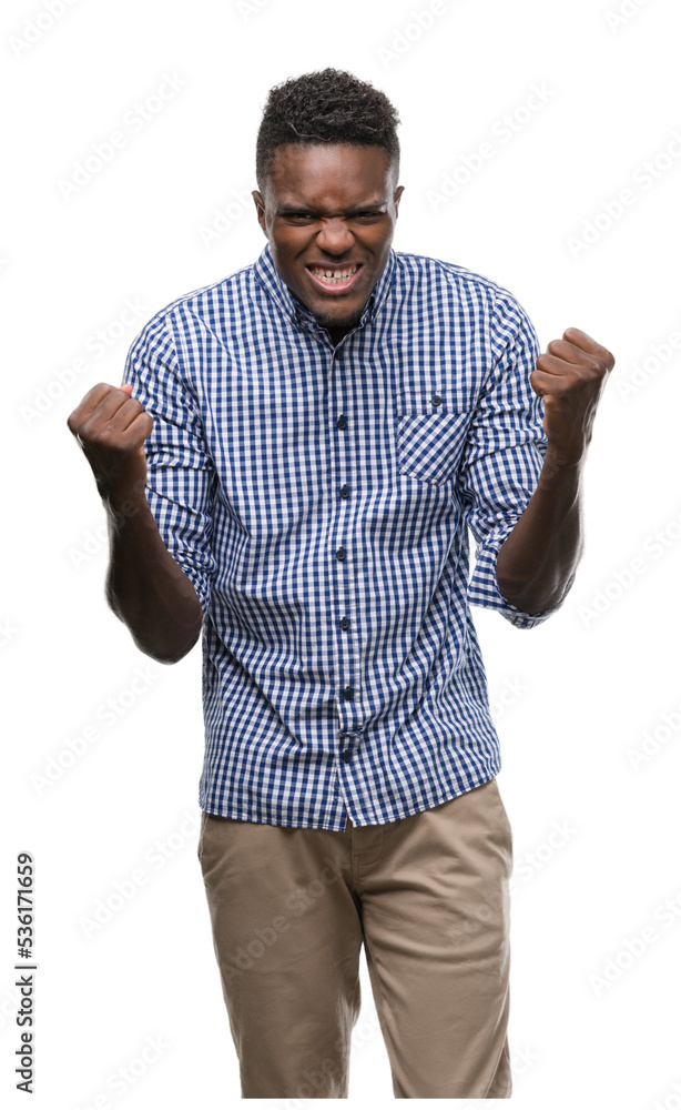 Fototapeta premium Young african american man wearing blue shirt celebrating surprised and amazed for success with arms raised and open eyes. Winner concept.