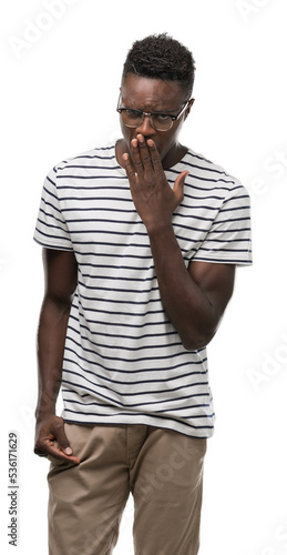 Young african american man wearing glasses and navy t-shirt bored yawning tired covering mouth with hand. Restless and sleepiness.