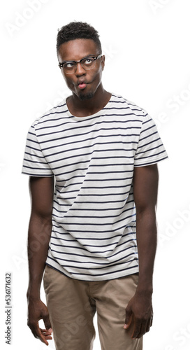 Young african american man wearing glasses and navy t-shirt making fish face with lips, crazy and comical gesture. Funny expression.