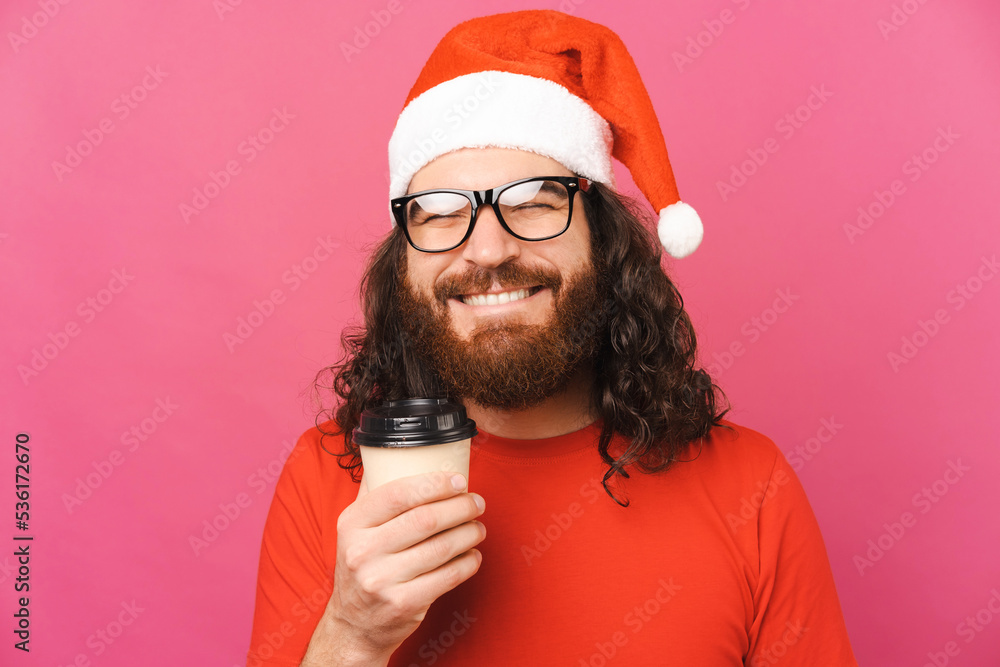 Handsome man wearing Christmas hat is holding tight a take away cup of coffee. Handsome man wearing Christmas hat is holding tight a take away cup of coffee.