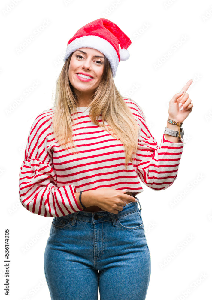 Young beautiful woman wearing christmas hat over isolated background with a big smile on face, pointing with hand and finger to the side looking at the camera.