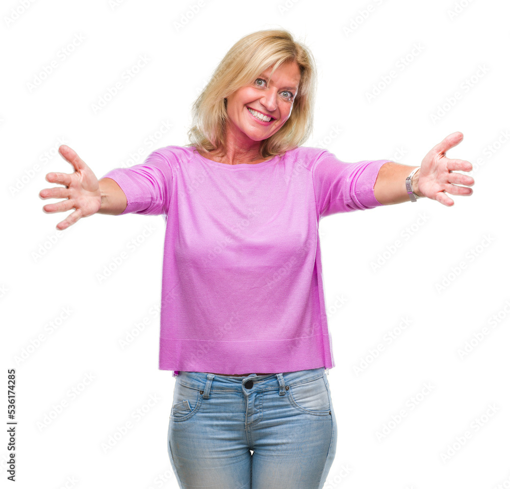 Fototapeta premium Middle age blonde woman over isolated background looking at the camera smiling with open arms for hug. Cheerful expression embracing happiness.