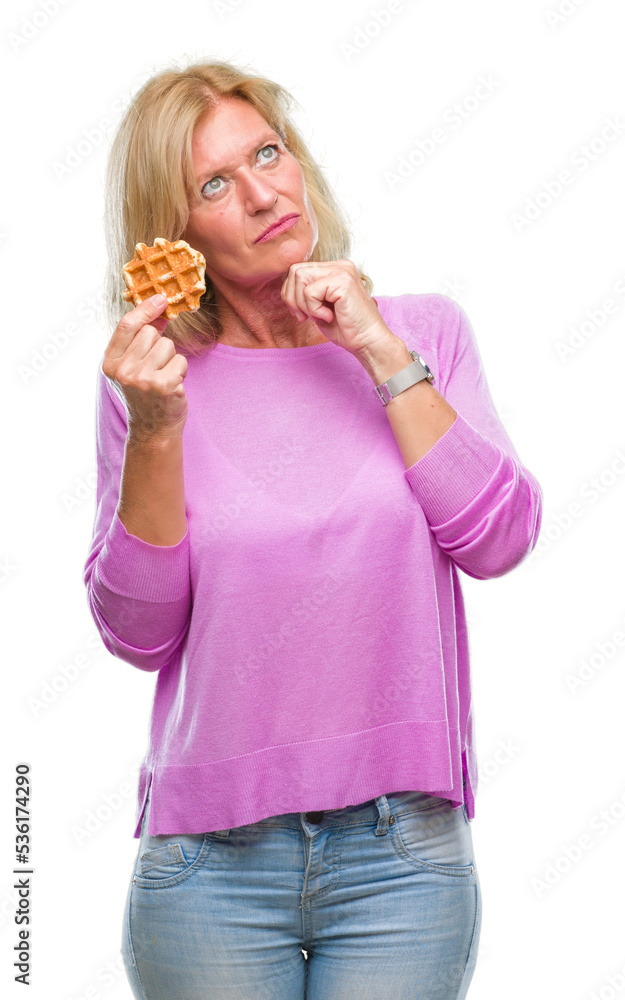 Middle age blonde woman eating sweet waffle over isolated background serious face thinking about question, very confused idea Middle age blonde woman eating sweet waffle over isolated background serious face thinking about question, very confused idea