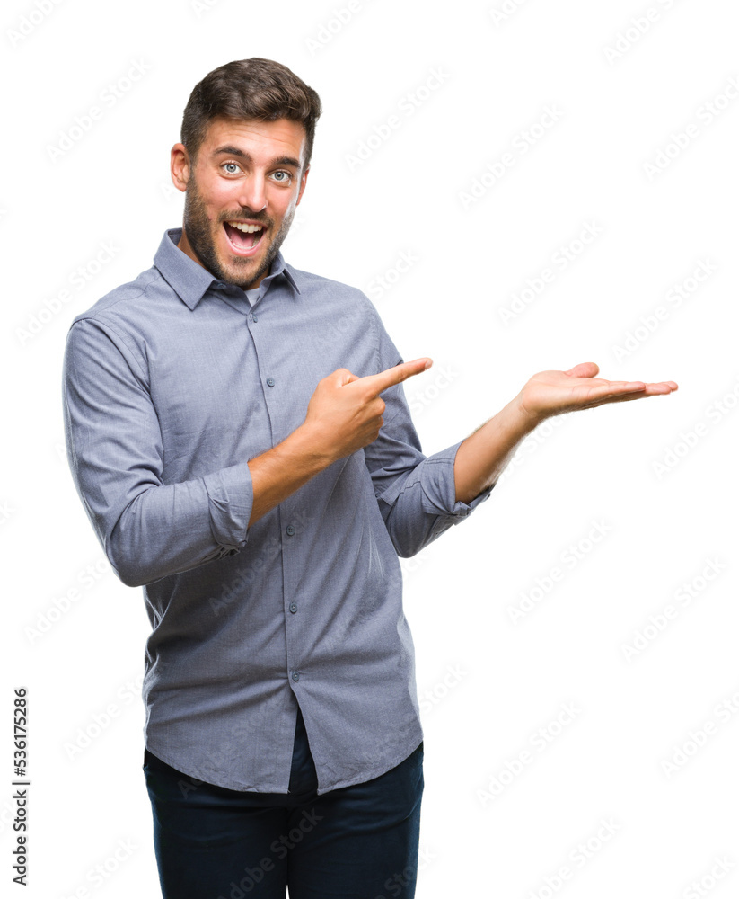 Young handsome man over isolated background amazed and smiling to the camera while presenting with hand and pointing with finger. Young handsome man over isolated background amazed and smiling to the camera while presenting with hand and pointing with finger.
