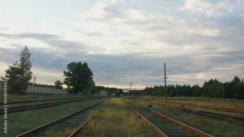 View of empty railroad tracks at a marshalling yard with a pipeline above them on a cloudy summer day