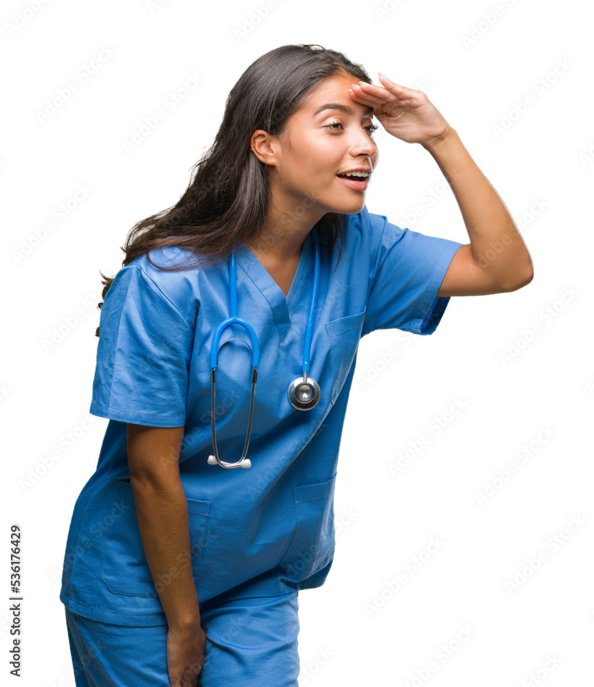 Young arab doctor surgeon woman over isolated background very happy and smiling looking far away with hand over head. Searching concept.