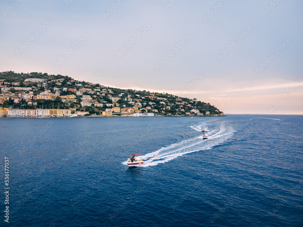 Obraz premium Three speedboats going next to the island in the evening