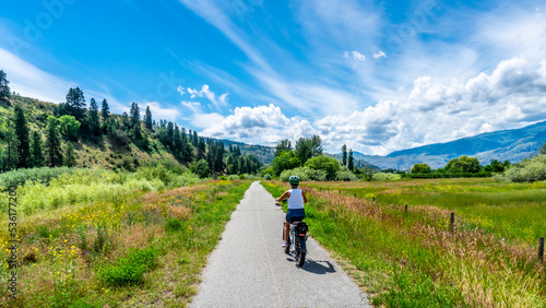 Woman on an e-bike on the trail along the Okangen River Canal between Oliver and Osoyoos in the Okanagen Valley of British Columbia,  Canada © hpbfotos