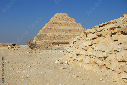 Pyramid of Saqqara, known as Pyramid of Steps, wall of ruins and horses in the background in southern Cairo, Egypt